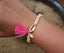Bracelet perles en bois avec un coquillage cauri doré et un pompon rose