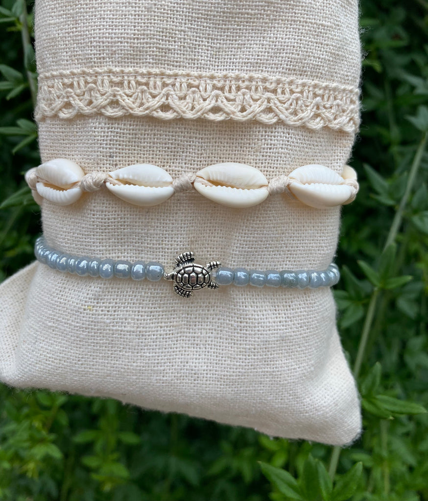 Chaînes de cheville beige en coquillages Cauris et tortue de mer. Perles gris clair nacré